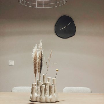 Seeblick: Ferienwohnungen Gronau Moderne eettafel met abstracte keramische vazen en een wandklok