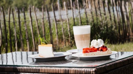Appartementhotel Seeblick: Bildergalerie Zwei Kuchenstücke und ein Glas Latte Macchiato auf einem Tisch im Freien