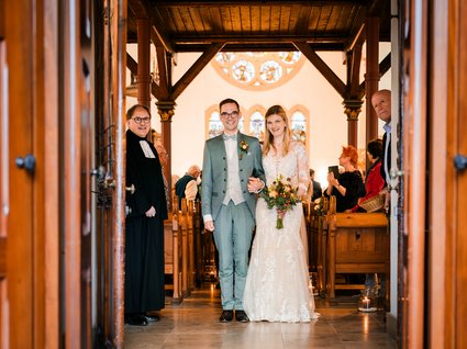 News vom Hotel direkt am See in NRW Brautpaar und Pfarrer stehen in einer Kirche nach der Trauung