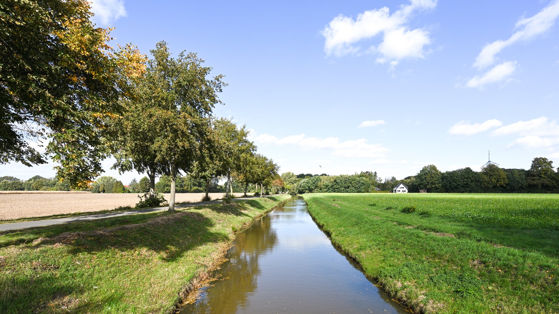 Ihr perfektes Fahrradhotel im Münsterland Kanal mit Bäumen, Wiesen und blauem Himmel bei sonnigem Wetter