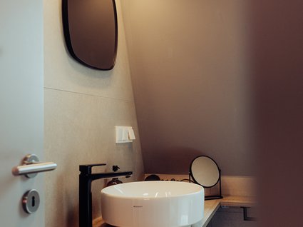 Aparthotel am See in Gronau Modernes Badezimmer mit Aufsatzwaschbecken, schwarzem Wasserhahn und Spiegel