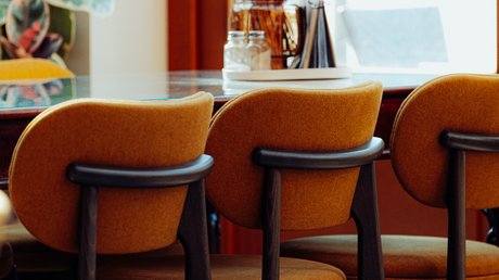 Appartementhotel Seeblick: Bildergalerie Drie bruine barkrukken voor een tafel met bloemen bij het raam