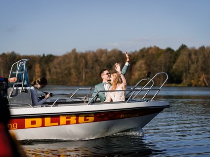 News vom Hotel direkt am See in NRW Brautpaar auf Rettungsboot auf einem See mit herbstlichem Wald im Hintergrund
