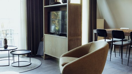 Appartementhotel Seeblick: Bildergalerie Moderne woonkamer met fauteuil, televisie, eettafel en open vakkenkast