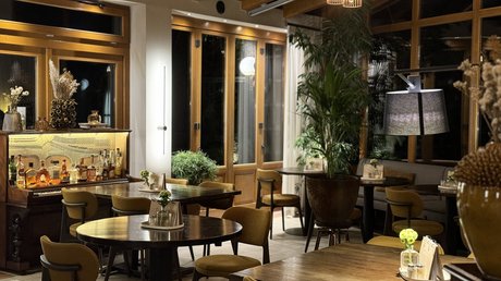 Appartementhotel Seeblick: Bildergalerie Gemütliche Bar mit holzvertäfelten Wänden, Tischen und gelben Stühlen bei Nacht